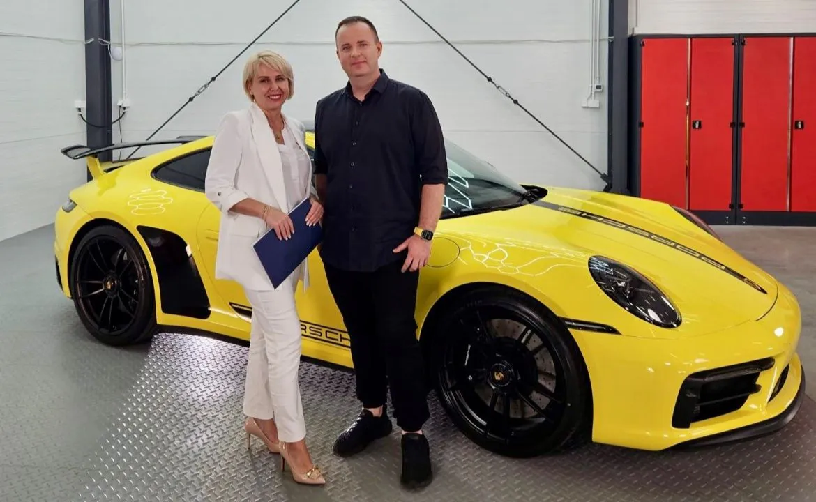Beata Wentura-Dudek wręcza dokumenty zwycięzcy loterii przy Porsche 911